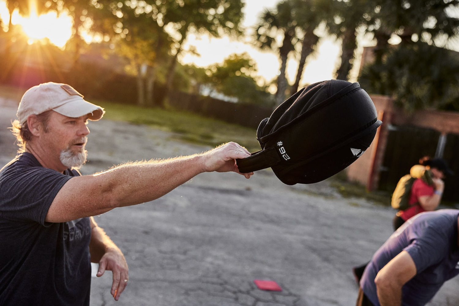 Man exercising outdoors with GORUCK 26-pound ruck sandbag at sunrise, outdoor fitness training
