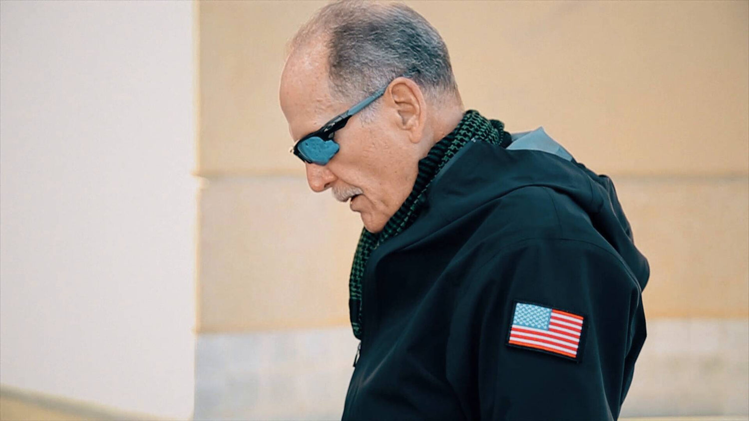 Man in tactical jacket with American flag patch wearing sunglasses, GORUCK rucking gear