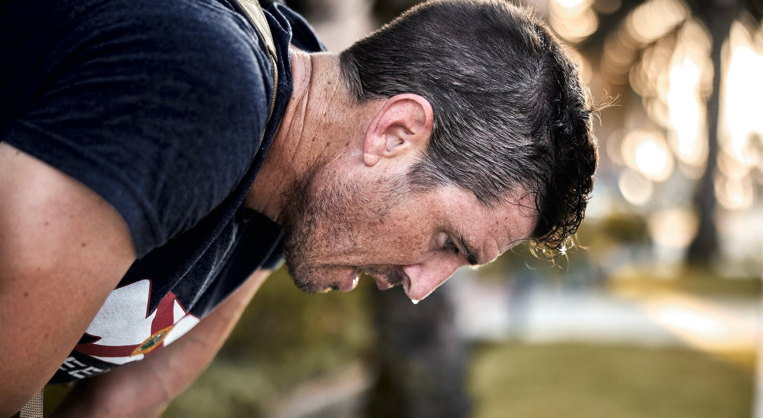 Man sweating outdoors in GORUCK workout shirt, showing intense rucking fitness effort