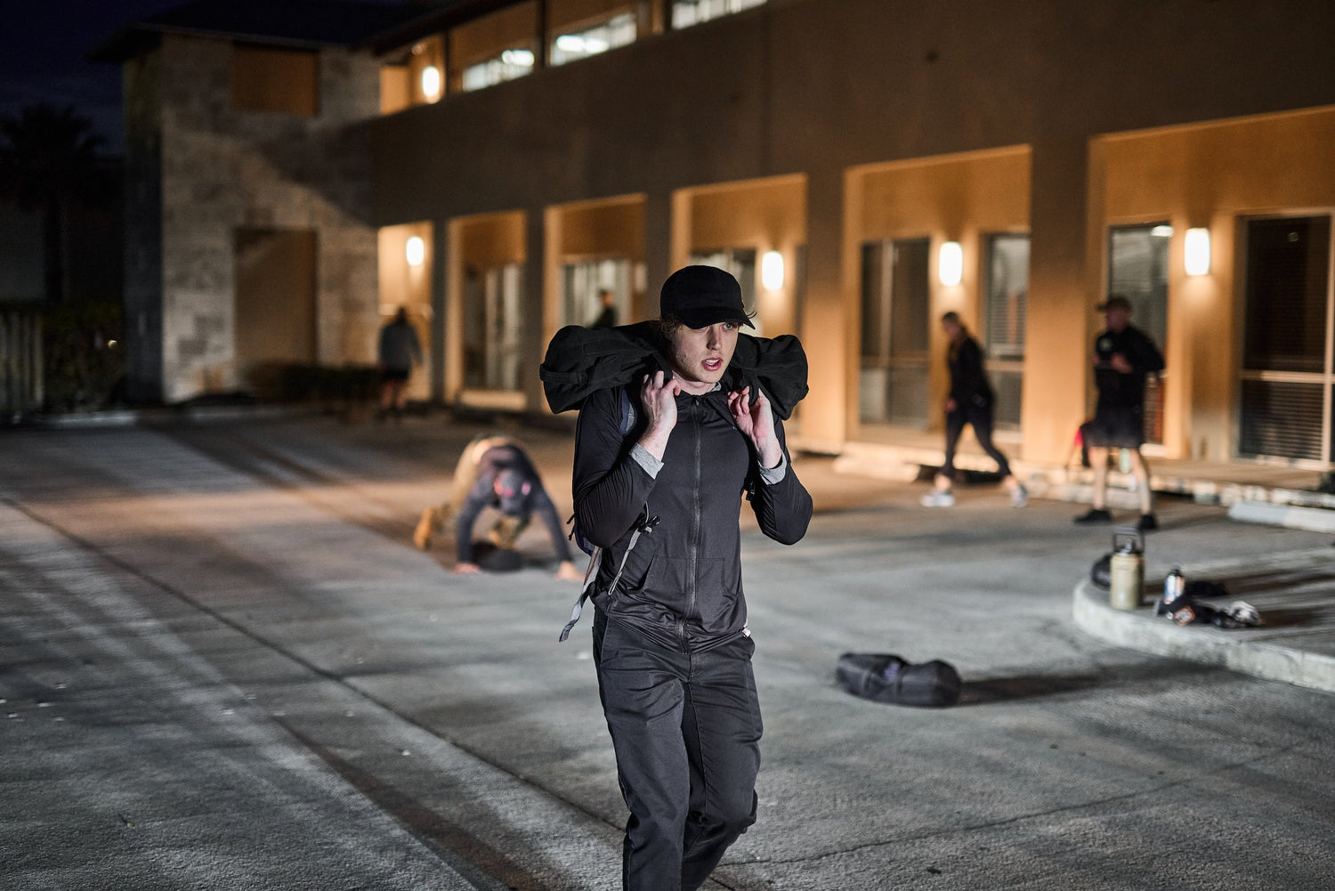 Person rucking with weighted sandbag at night during GORUCK club outdoor fitness event
