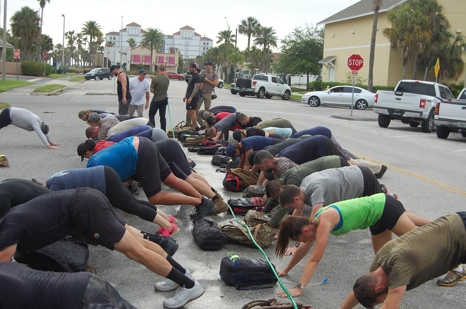 GORUCK event participants doing outdoor group exercise with rucksacks on a city street
