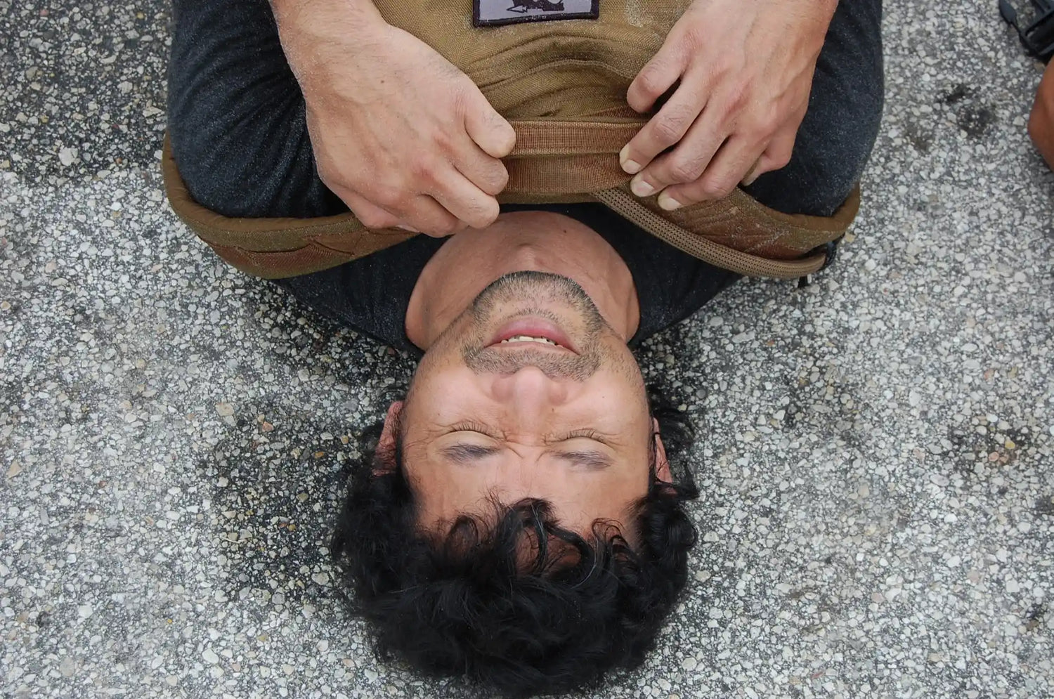 Man lying on pavement wearing a GORUCK backpack, demonstrating rucking endurance gear