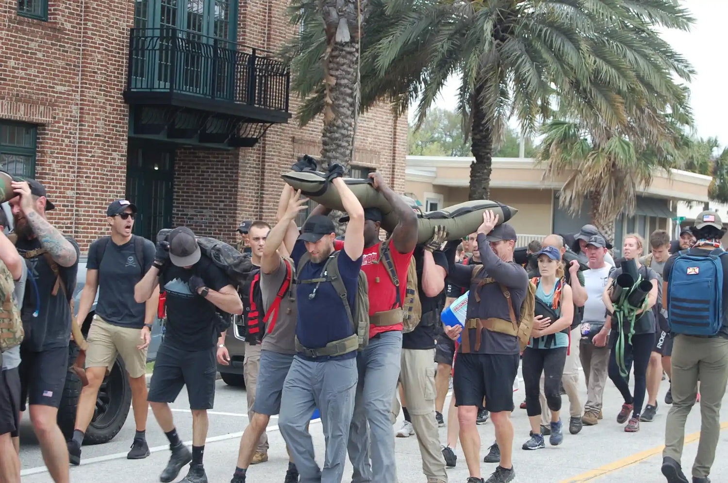 Group rucking event with participants carrying sandbags, wearing GORUCK gear outdoors