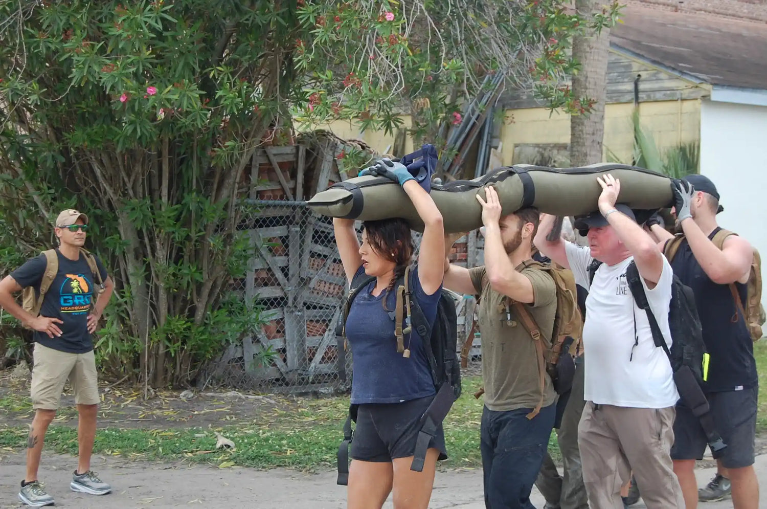 GORUCK team rucking outdoors with sandbag, participants wearing backpacks and athletic gear
