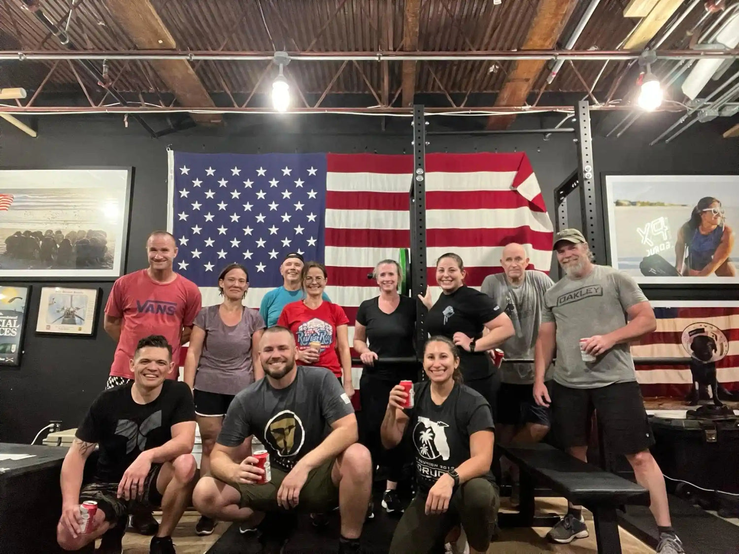 Group of people posing in a gym with American flag, GORUCK rucking event atmosphere
