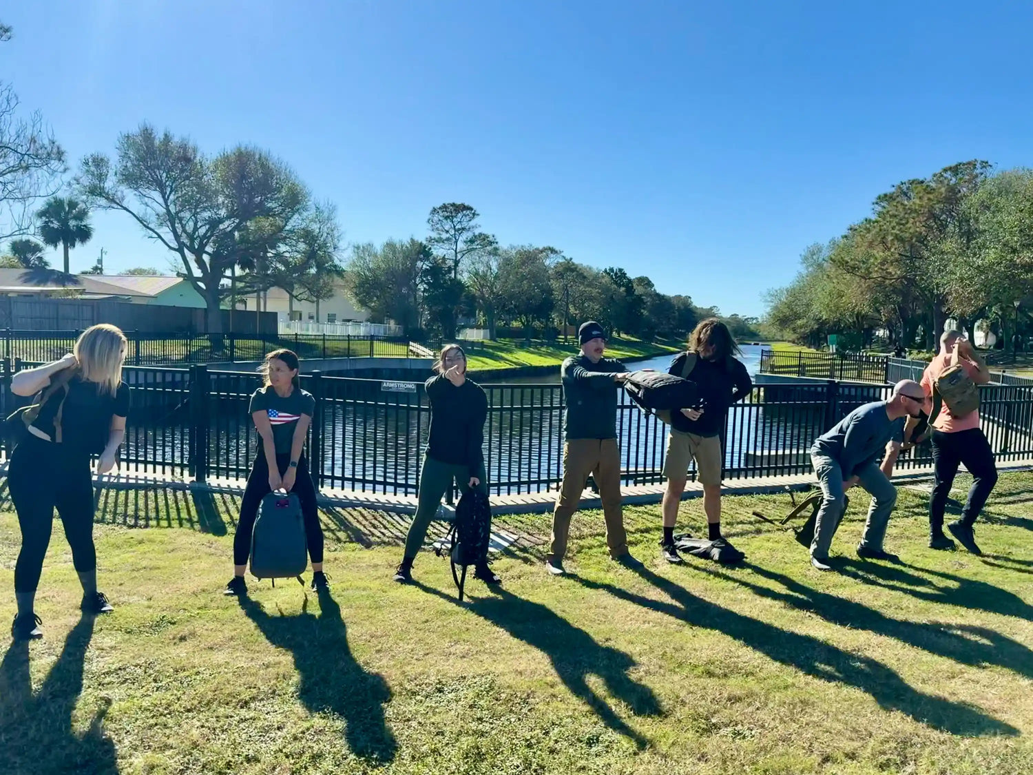 Group outdoor rucking workout with GORUCK gear by a canal on a sunny day