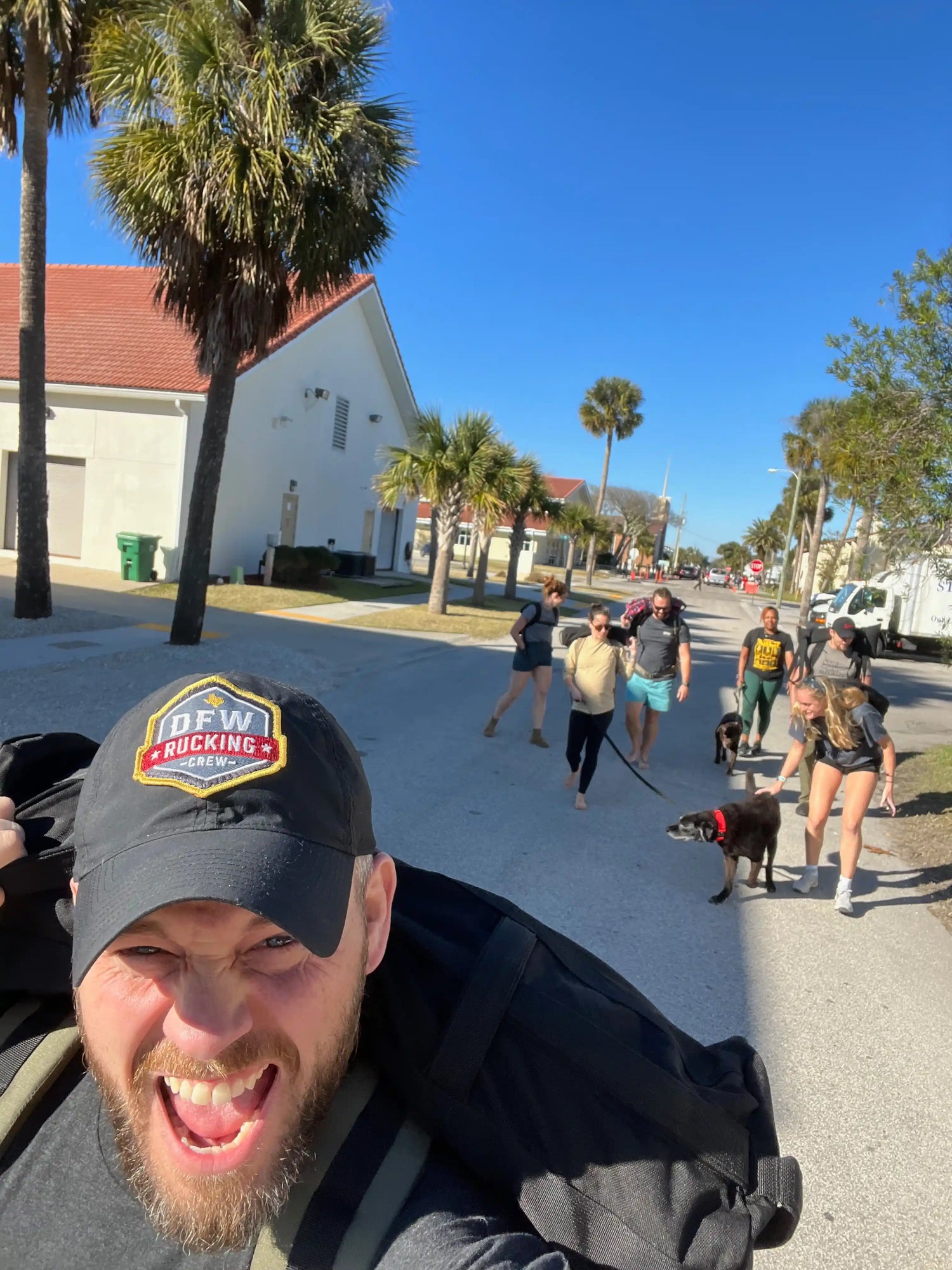 Group rucking outdoors with GORUCK gear under palm trees on a sunny street.