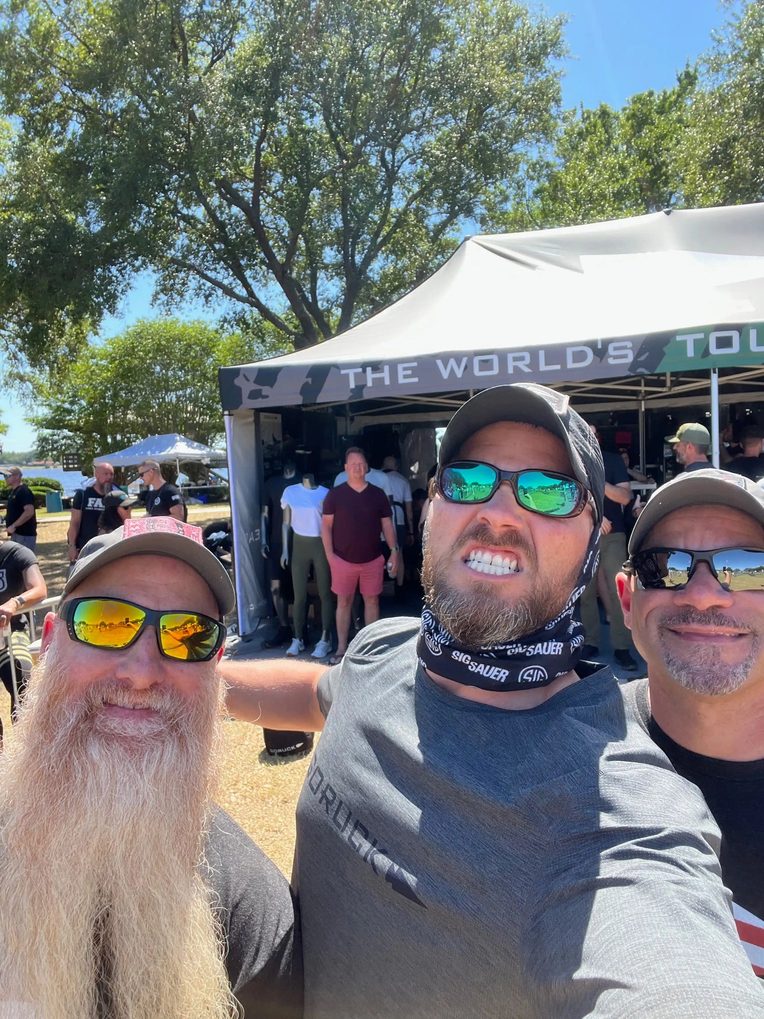 Group of men wearing GORUCK gear smiling at outdoor GORUCK event with branded tent