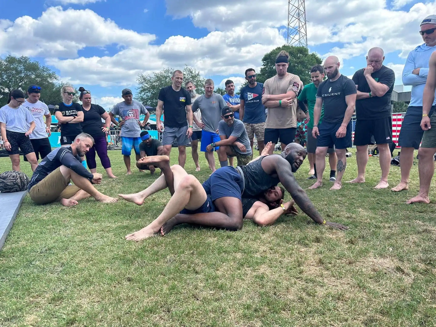 Outdoor Brazilian jiu-jitsu training session with instructor demonstrating grappling techniques on grass