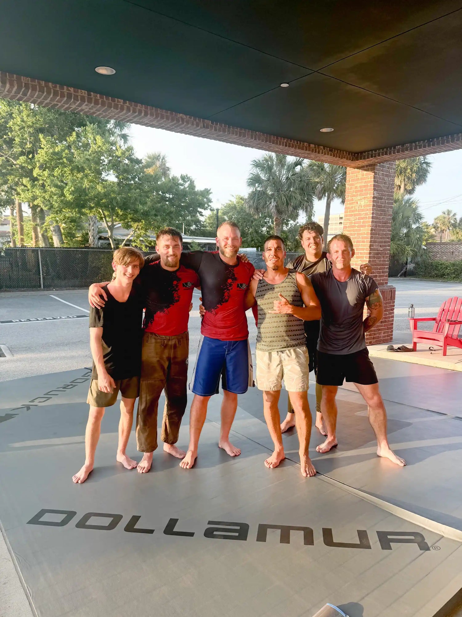 Group of six men on GORUCK training mat outdoors, smiling after rucking or workout session