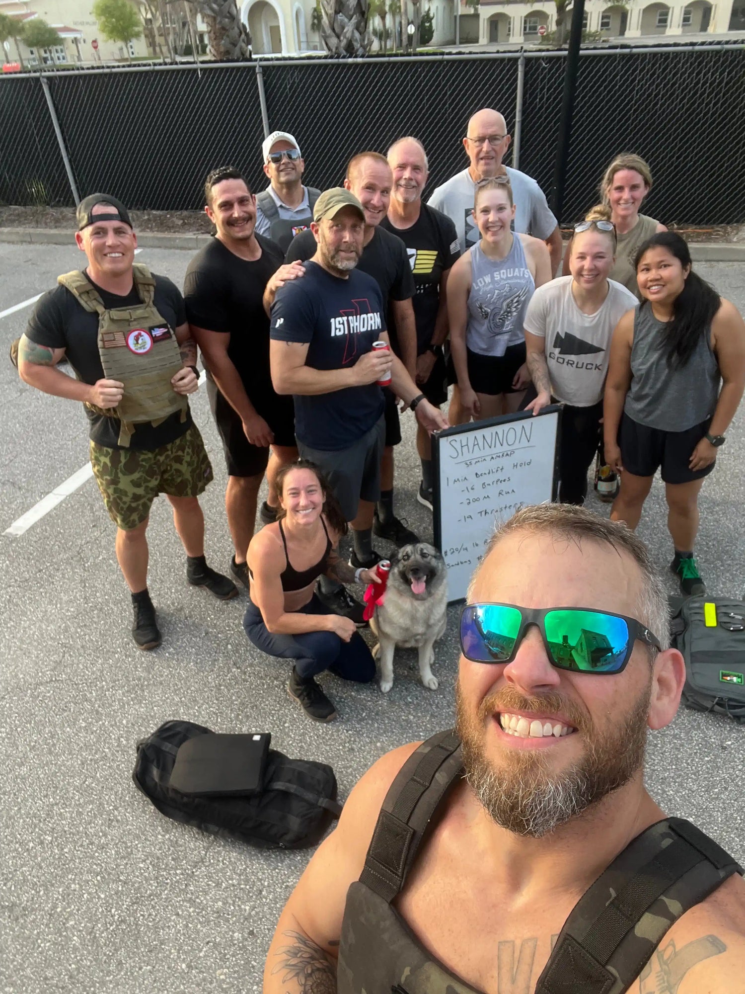 GORUCK group in outdoor workout, smiling members posing with dog and gear, community fitness