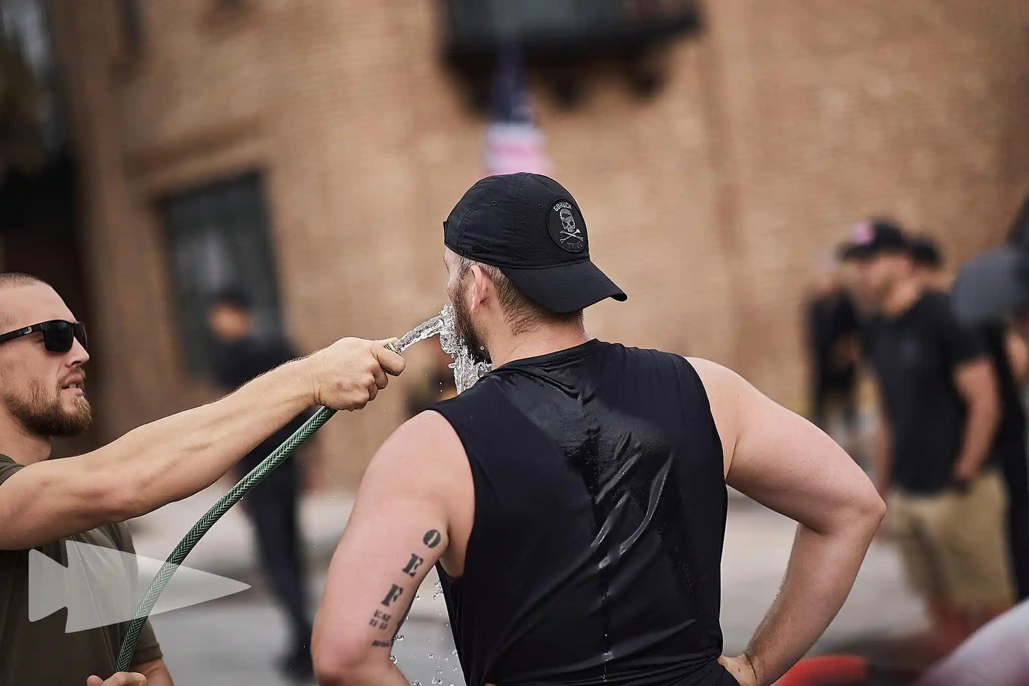 GORUCK athletes hydrating with a hose during an outdoor rucking training event