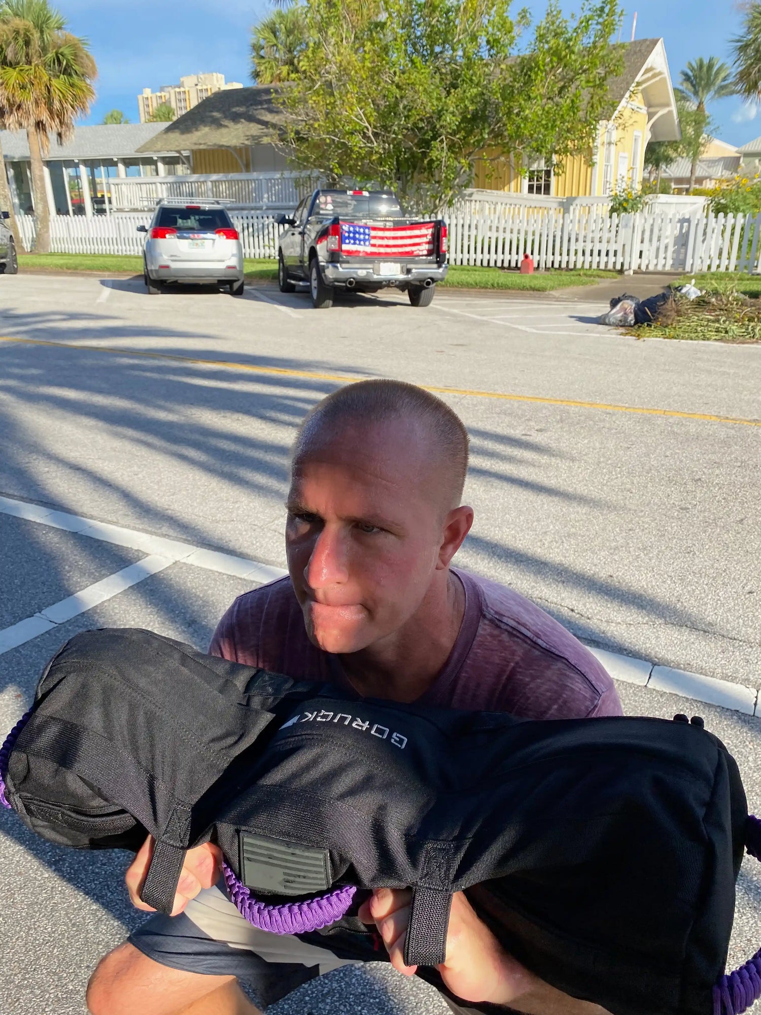 Man outdoors lifting GORUCK sandbag, showcasing durable rucking gear in sunlight