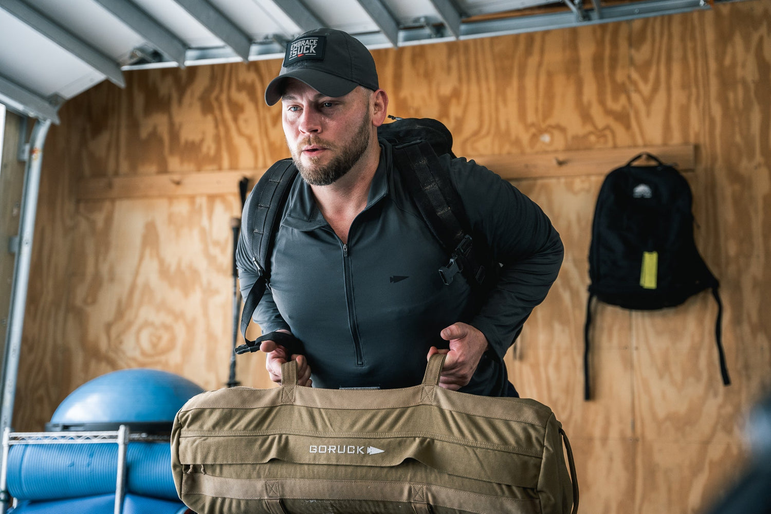 Man training indoors with GORUCK gear bag and backpack, showcasing durable rucking equipment
