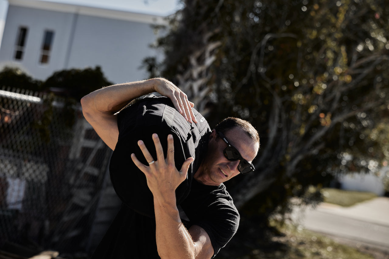 Man carrying GORUCK sandbag on shoulder outdoors, demonstrating rucking gear