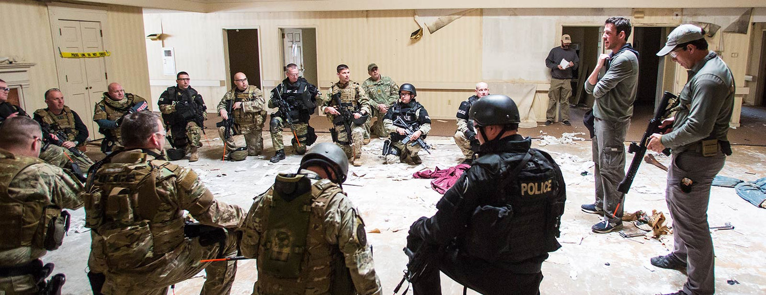 SWAT team and police officers in tactical gear gathered for a training briefing indoors, GORUCK style
