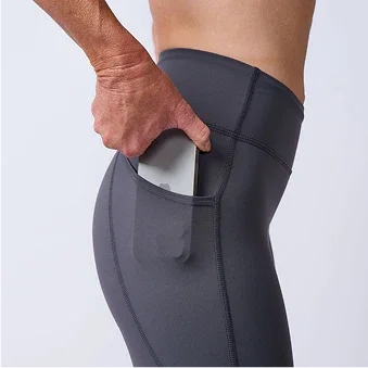 Athlete putting phone in pocket of gray GORUCK workout tights