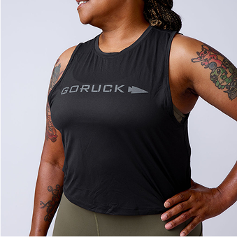 Close-up of woman wearing black GORUCK sleeveless workout shirt with logo, showcasing arm tattoos