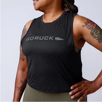 Woman wearing black GORUCK sleeveless tank top, showing tattoos, promoting rucking gear.