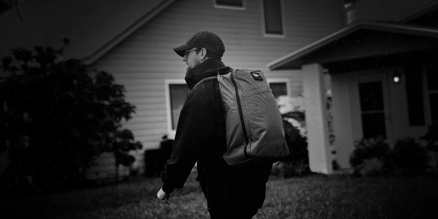 Man wearing GORUCK rucksack backpack outdoors in front of a house
