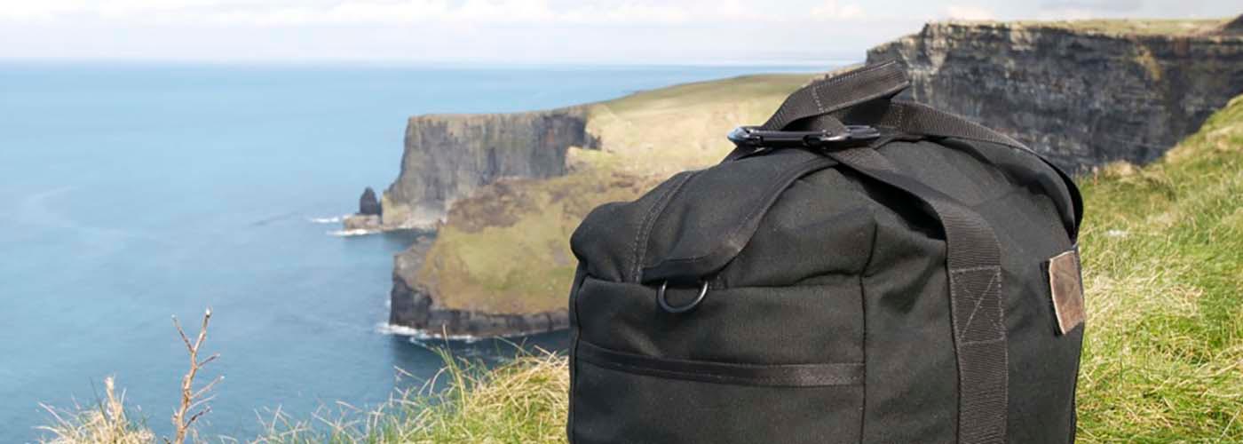 GORUCK rugged black rucksack on grassy cliffside overlooking ocean and coastal cliffs
