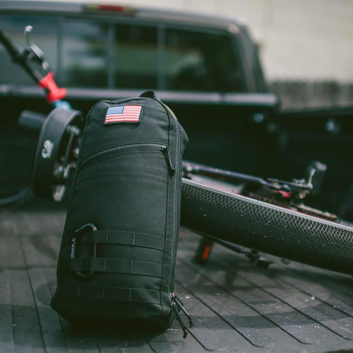 GORUCK black rucksack with USA flag patch on truck bed, bicycle tire in background