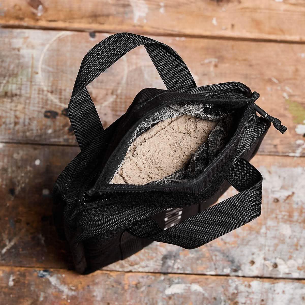 GORUCK black sandbag open, filled with sand, on a rustic wooden surface