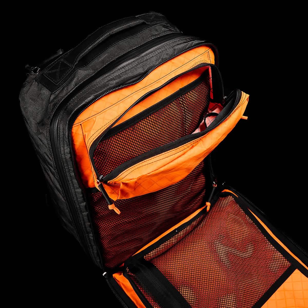 The GR2 USA x Carryology - Ultra Black backpack features durable UHMWPE fabric, an orange interior, and unzipped mesh pockets with organized compartments.