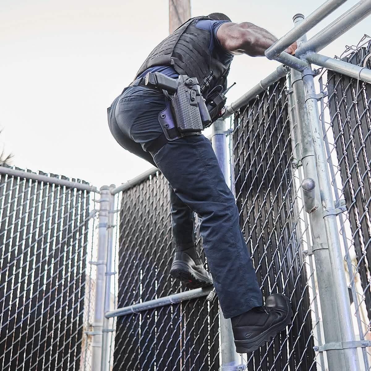 Man in tactical gear scaling a metal fence, showcasing durable GORUCK rucking equipment.