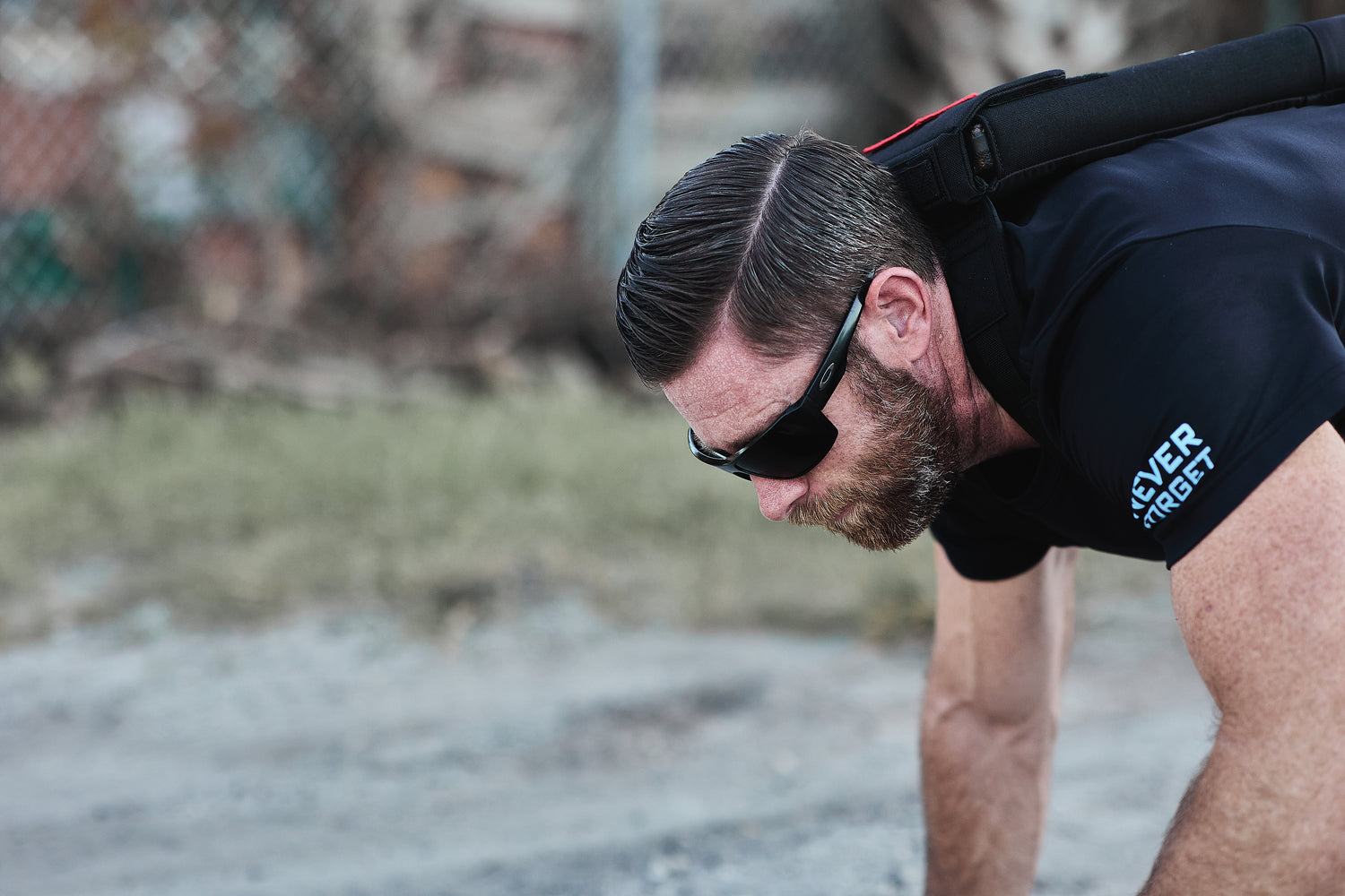 Man wearing sunglasses and a black shirt does push-ups outdoors, highlighting upper body strength, while training with the RPC Long + 30LB (Long) Plate Bundle.