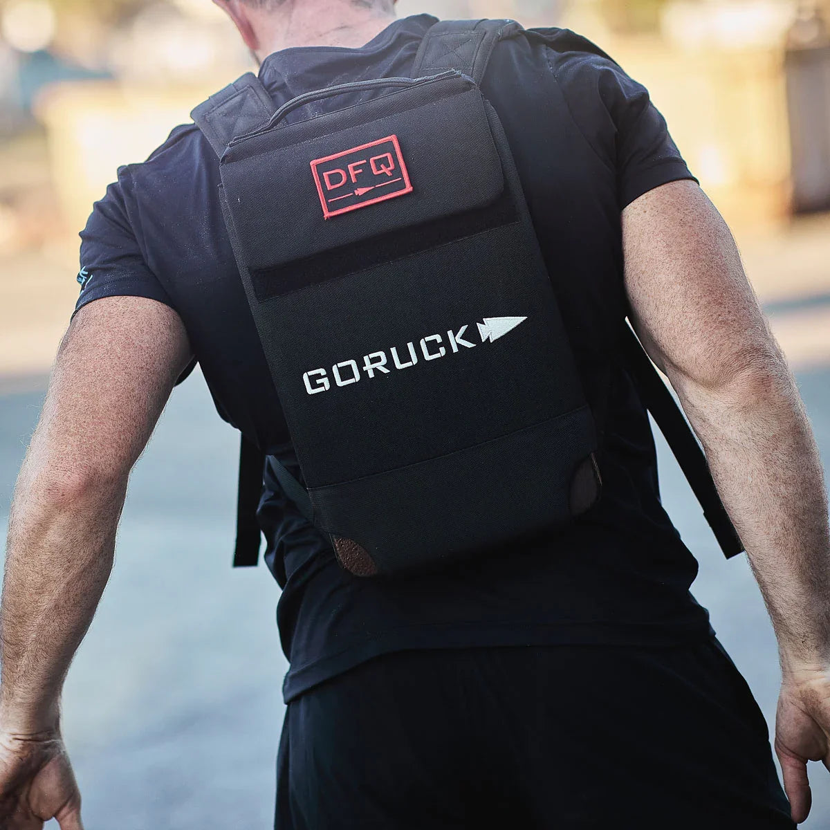 Man wearing black GORUCK rucksack with DFQ patch on back outdoors