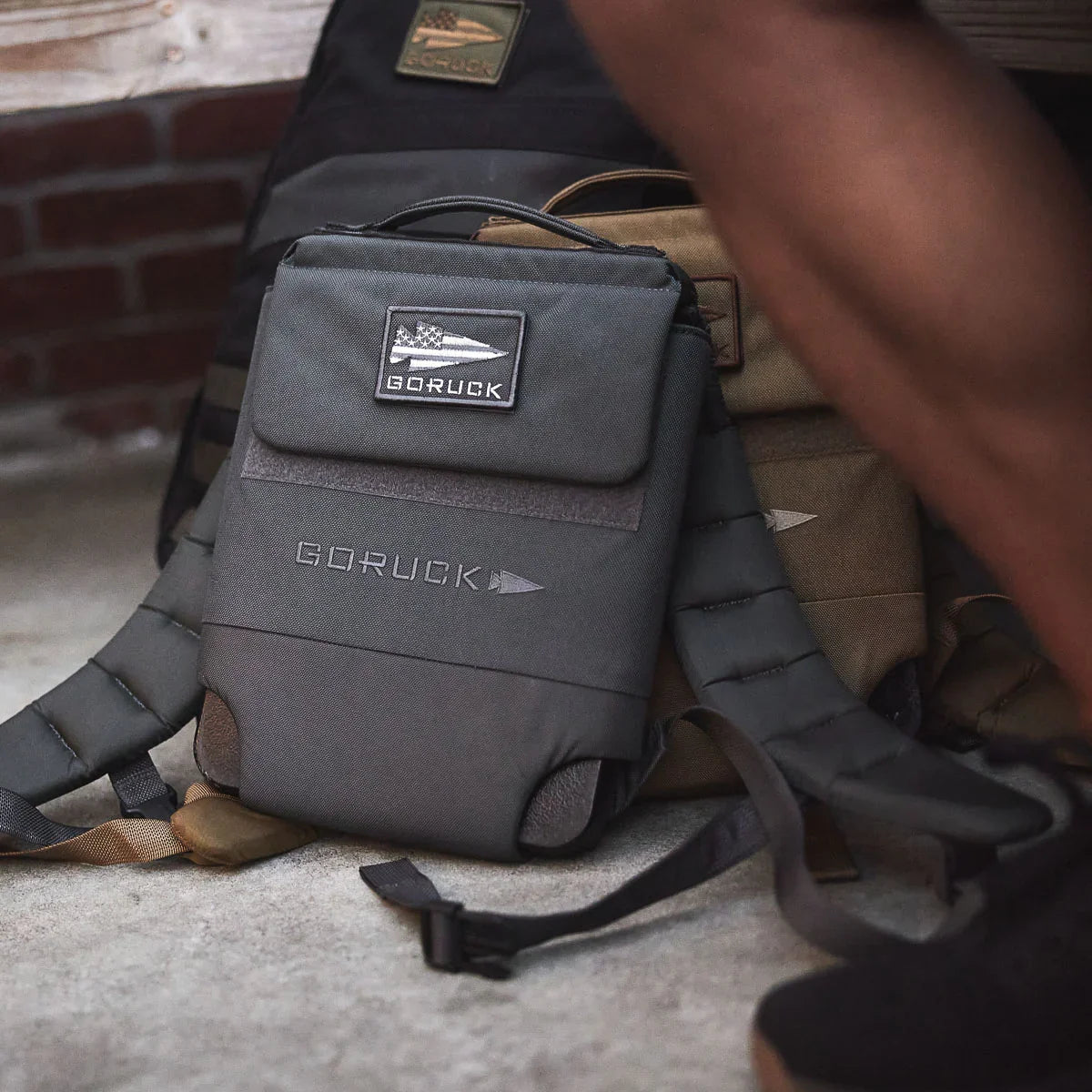 Close-up of GORUCK branded tactical backpacks with durable straps on concrete floor in indoor setting