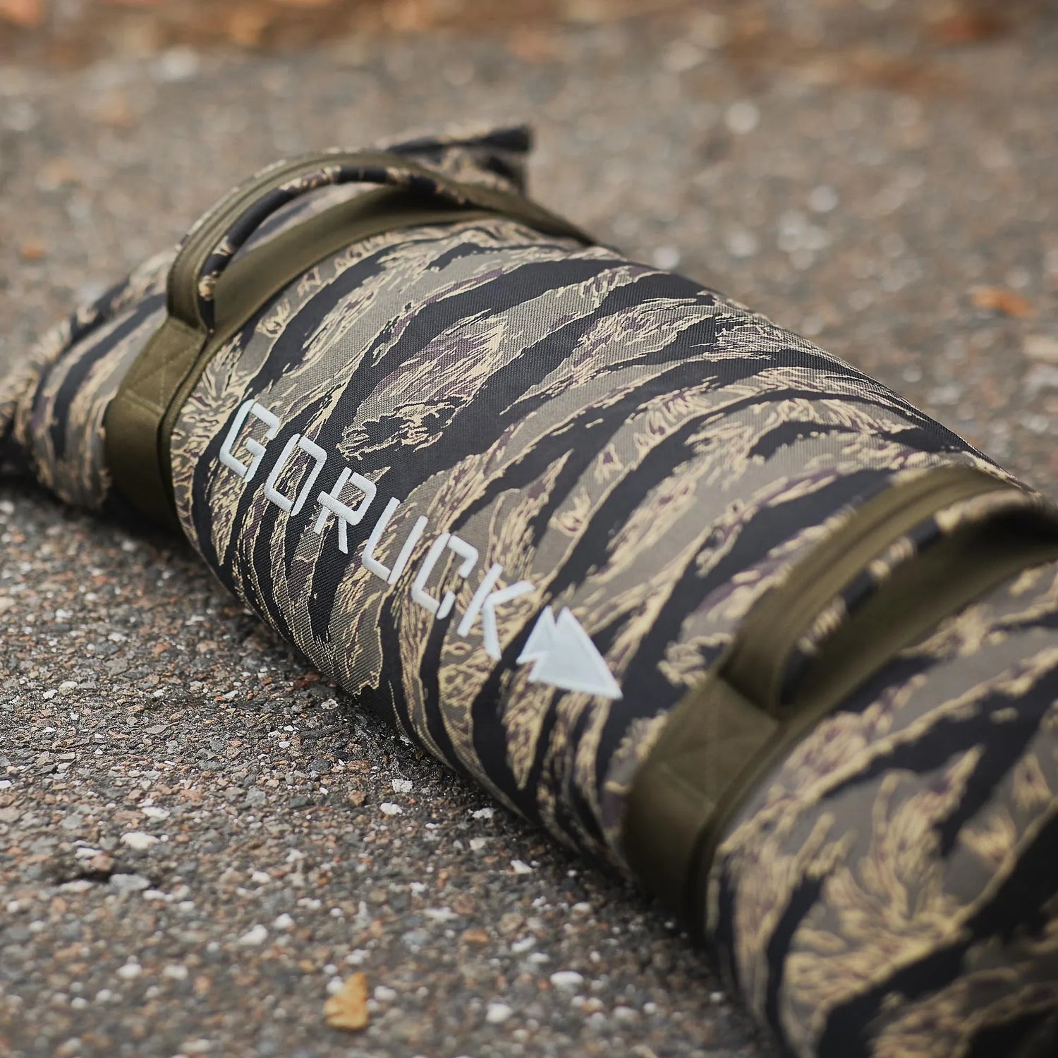 GORUCK camouflage sandbag with handles on pavement, rugged outdoor rucking gear