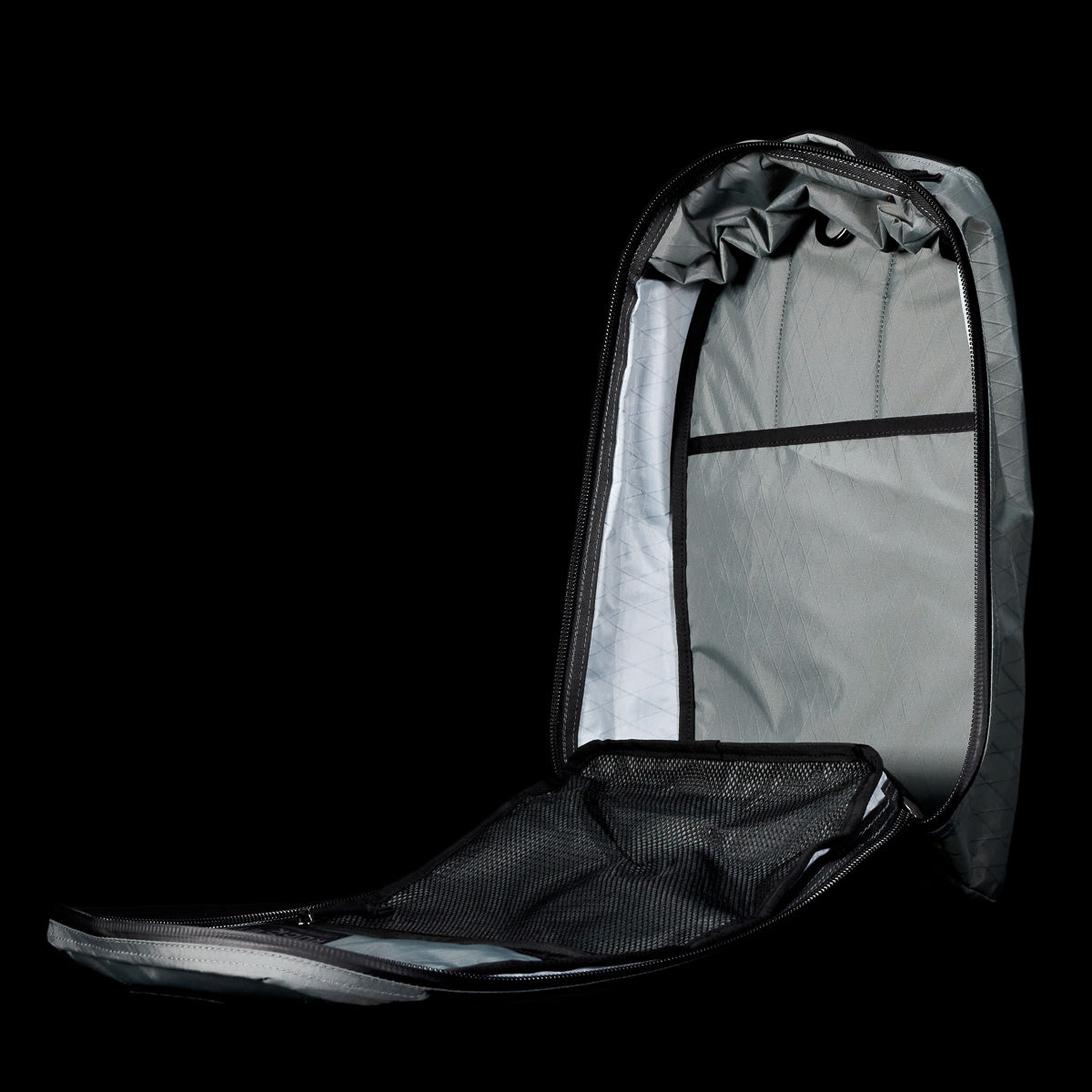 The Bullet X-PAC daypack in black and gray is shown open on a black background, revealing its interior compartments and weatherproof design.