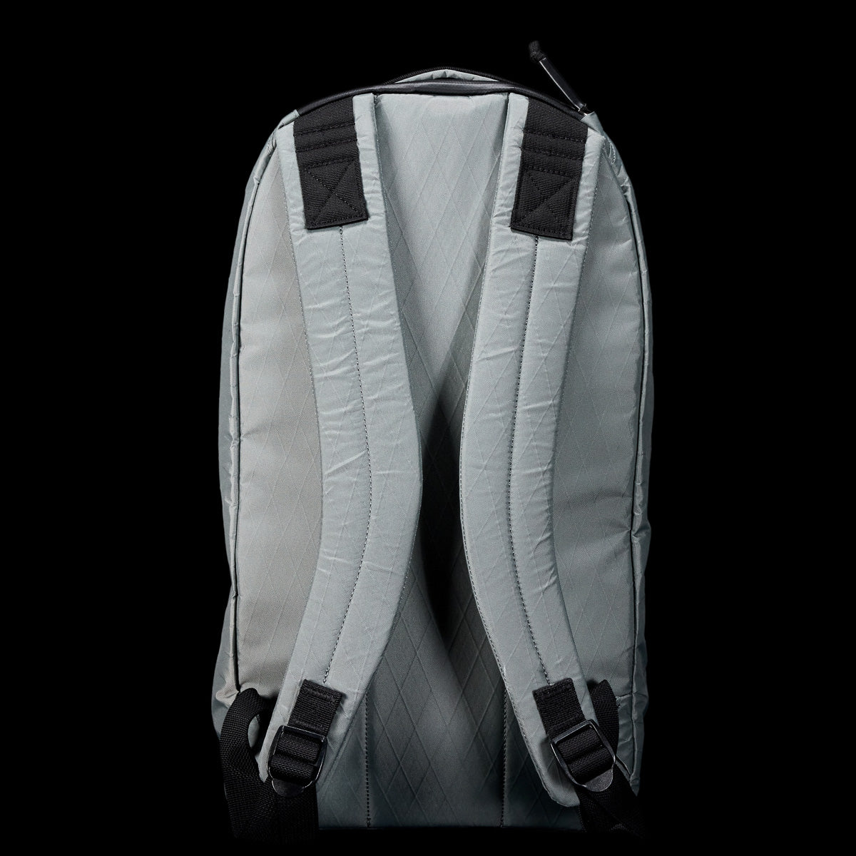 The Bullet X-PAC, a light gray weatherproof daypack, is shown from the back with padded shoulder straps visible against a black background.