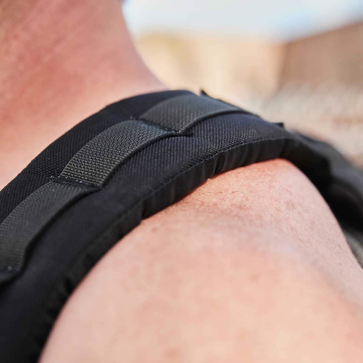 Close-up of a black strap from the GORUCK GR1 USA - Cordura (The Original Ruck) resting on a person's shoulder, reminiscent of Special Forces gear, outdoors.
