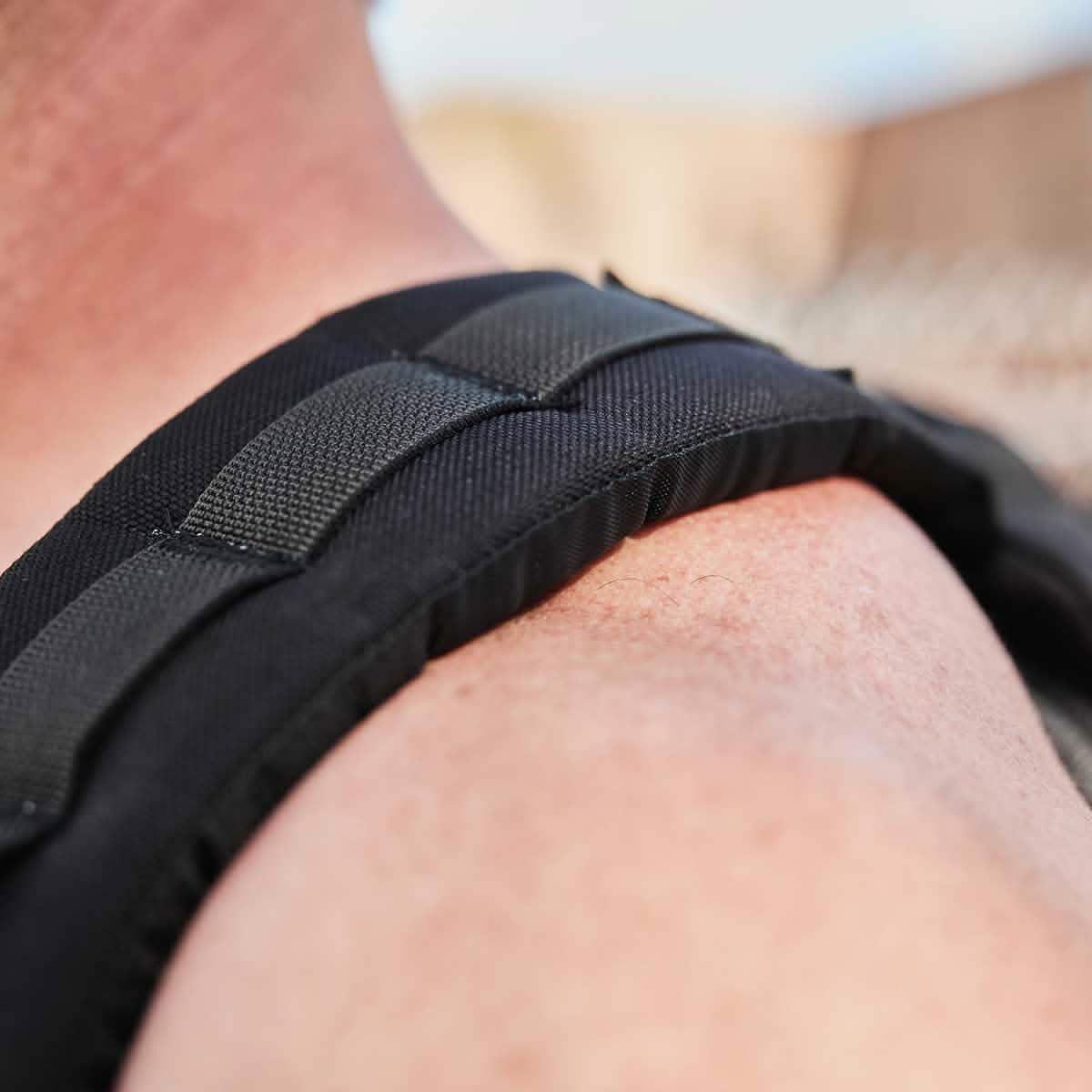 Close-up of a black padded rucksack shoulder strap on a person's bare shoulder, showcasing durable GORUCK gear