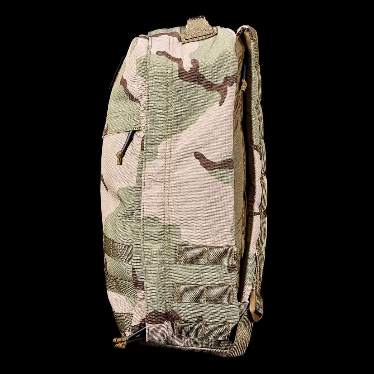 Side view of beige and brown camouflage GORUCK tactical rucksack with MOLLE webbing against black background