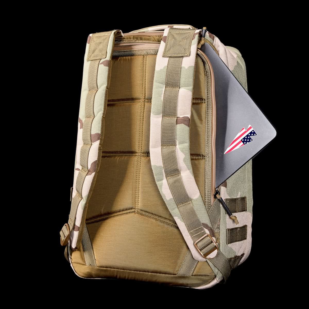 The GR1 USA - Ballistic Nylon Cordura (The Original Ruck) 210D Back Panel is a camo everyday carry rucksack featuring padded straps and a laptop partially tucked into its back compartment.