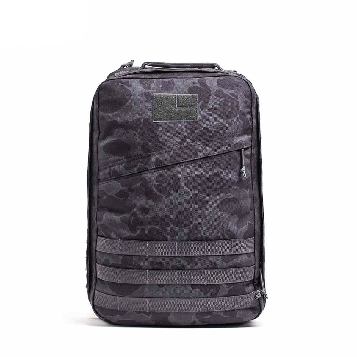 The GR1 USA - Cordura is a black and gray camouflage-patterned rucksack with zippers and a top handle, displayed on a white background.
