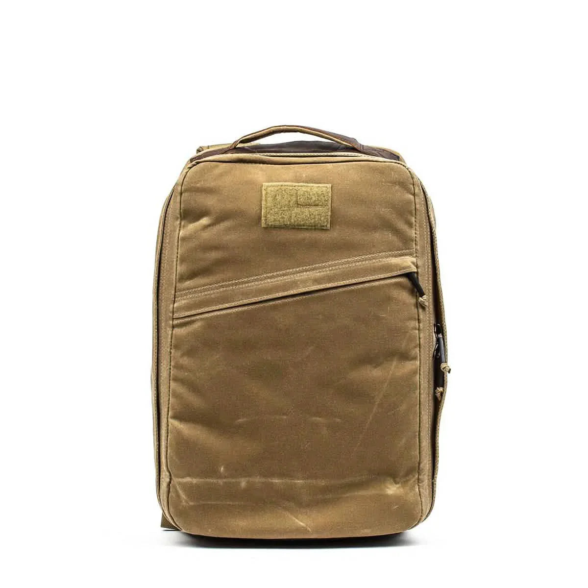 GORUCK rugged field tan rucksack with diagonal zippered pocket and top handle on white background