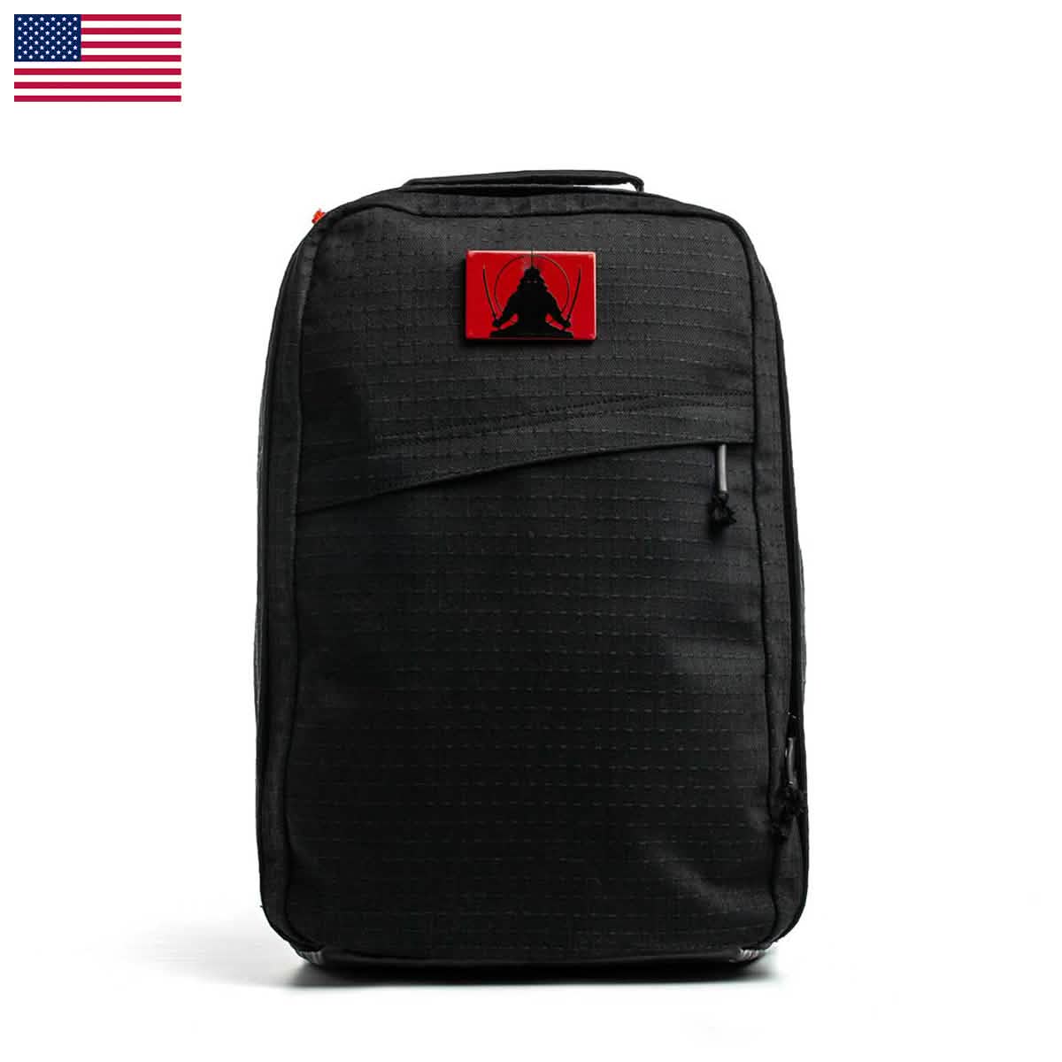 The GR1 USA x Carryology - GRXC2 Samurai is a black backpack with a red patch and an American flag in the top left corner, made from premium Japanese cotton for outstanding durability.