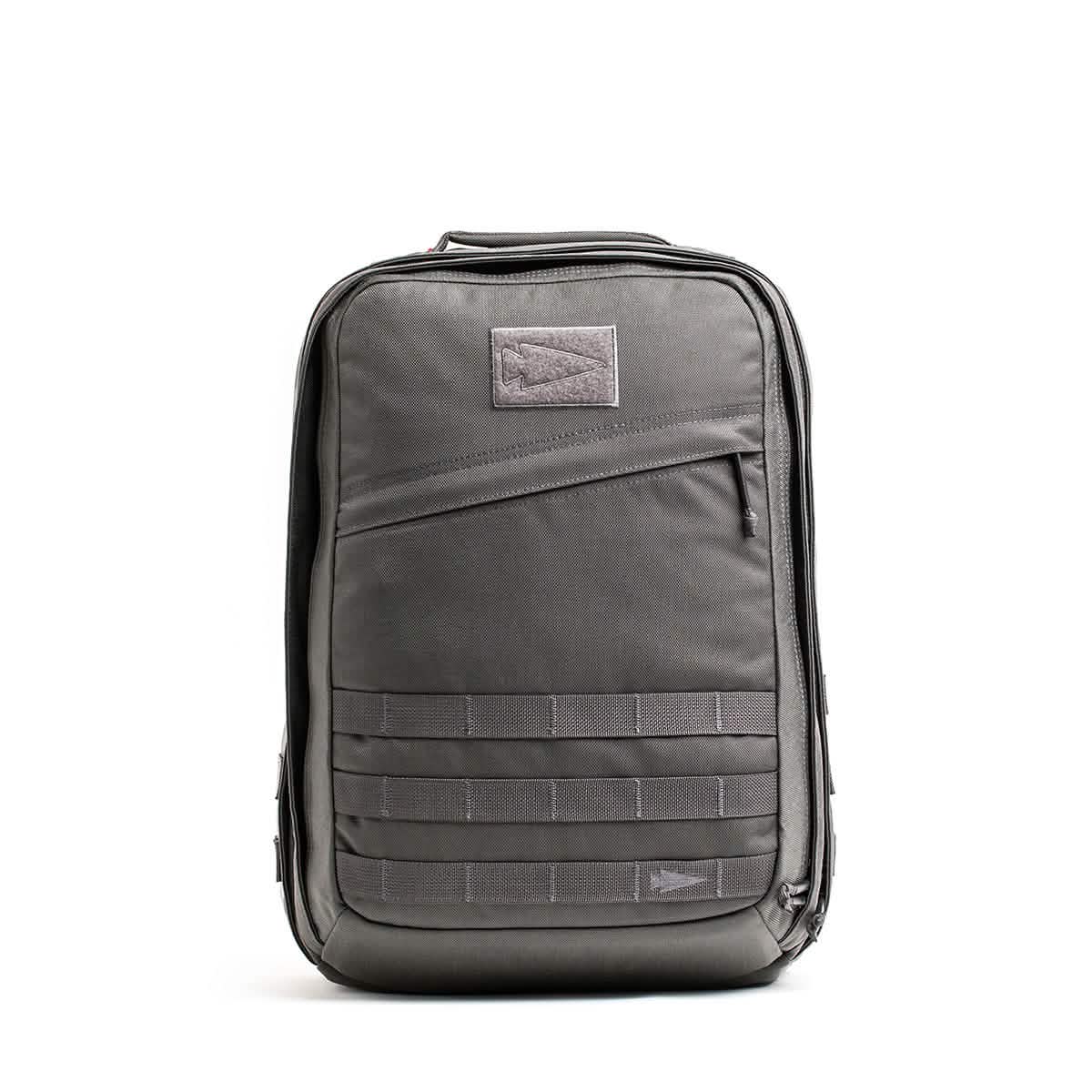 The GR2 - Cordura by GORUCK is a sleek grey backpack designed with inspiration from those favored by Special Forces. It stands upright, showcasing a front compartment with horizontal strap details and a subtle patch near the top. This minimalistic yet sturdy ruck is perfect for any adventure.