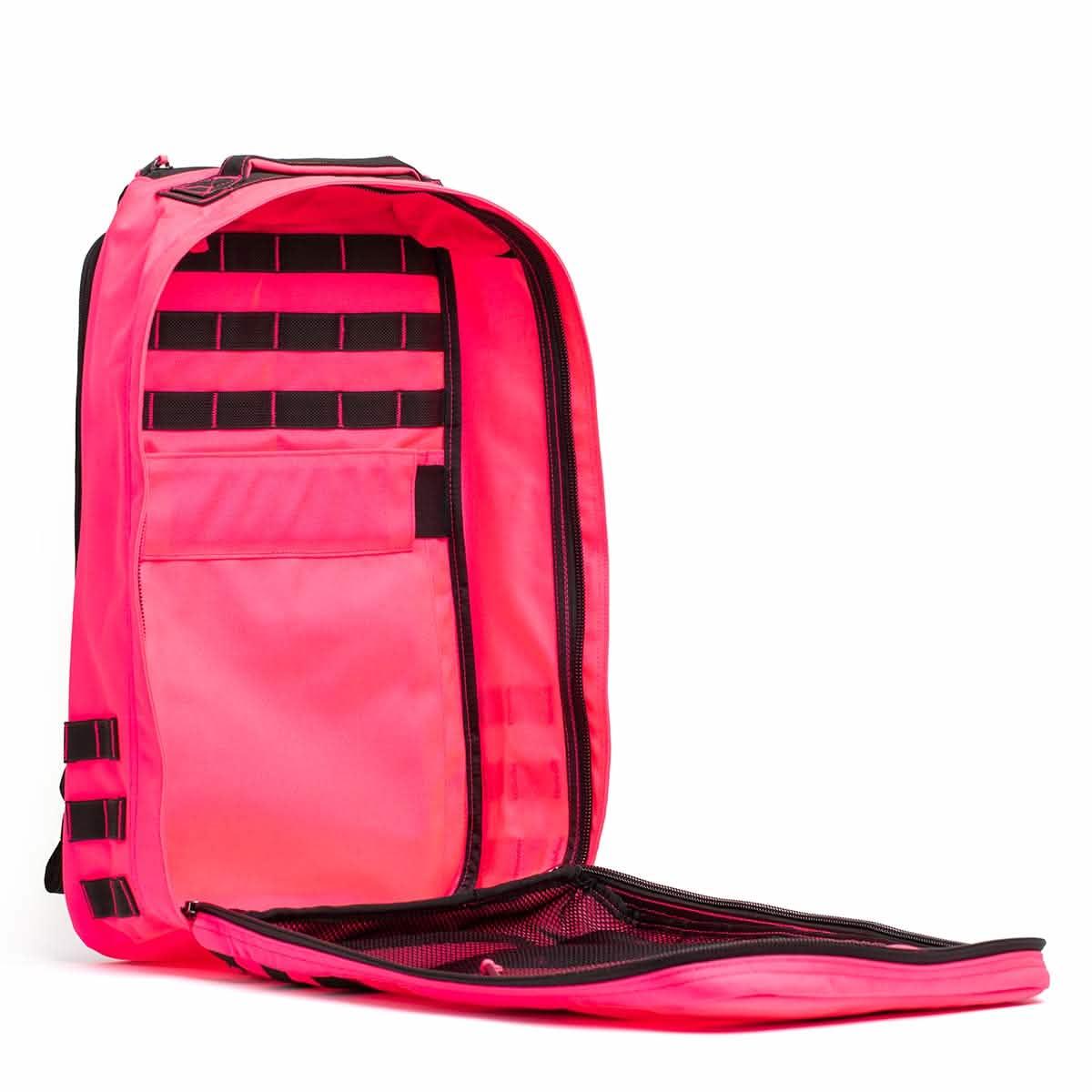 Open hot pink GORUCK rucksack showing interior compartments, mesh pocket, and black webbing