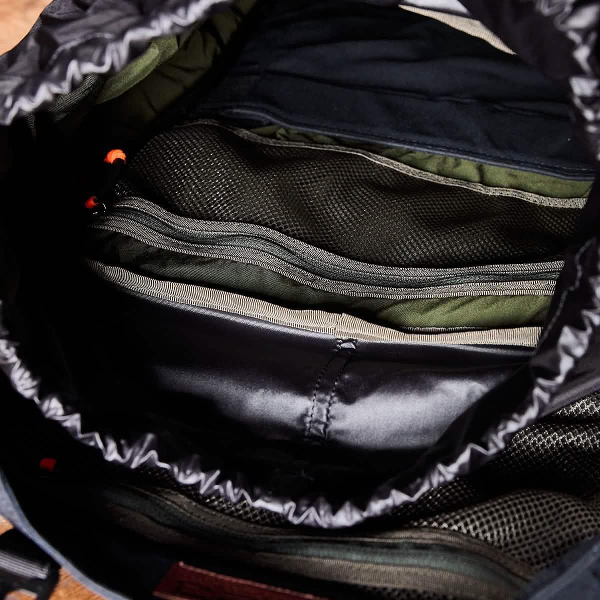 Close-up of organized interior compartments in a GORUCK tactical backpack with black and olive green fabric