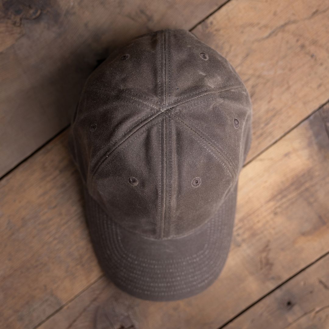 Tac Hat - Heritage with visible stitching, placed on a rustic wooden surface and viewed from above.