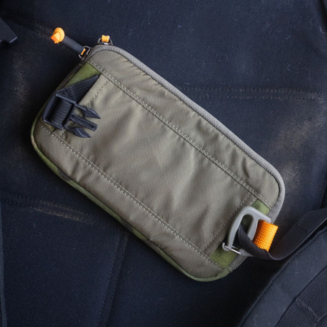 Sternum / Belt Pouch - CORDURA in khaki with black clips and orange accents sits on a dark fabric surface—perfect for rucking or keeping essentials hands-free.