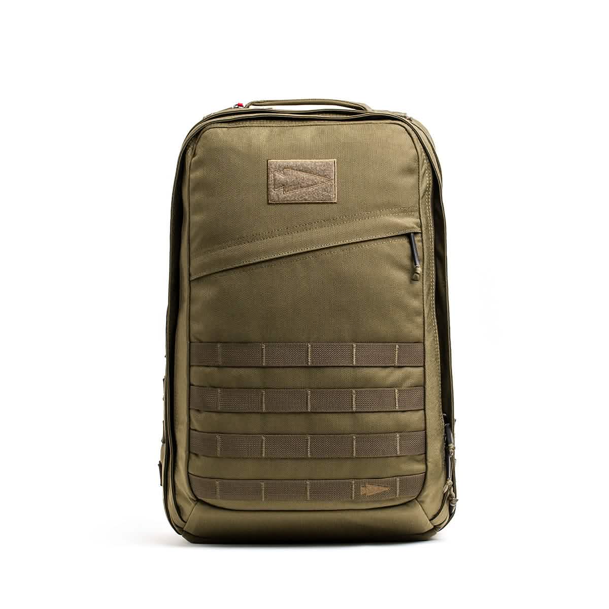 The GR2 by GORUCK is a green tactical backpack crafted with the quality needed for Special Forces. It showcases a rectangular design, multiple compartments, and MOLLE webbing for attachments. This backpack includes a front zipper pocket, is carry-on compliant in size, and features a plain patch area on top along with a fabric carrying handle.