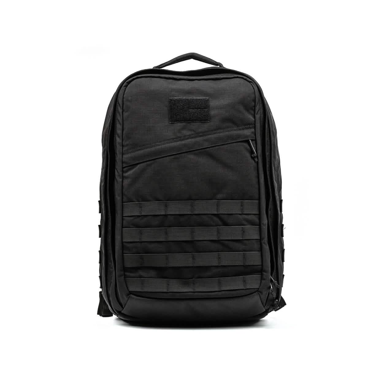 The GR2 by GORUCK is a black tactical backpack designed with Special Forces quality. It includes multiple compartments, a front zipper pocket, horizontal webbing, and a top carry handle. Its rugged design makes it perfect for outdoor adventures and it's also carry-on compliant. The background remains plain white.