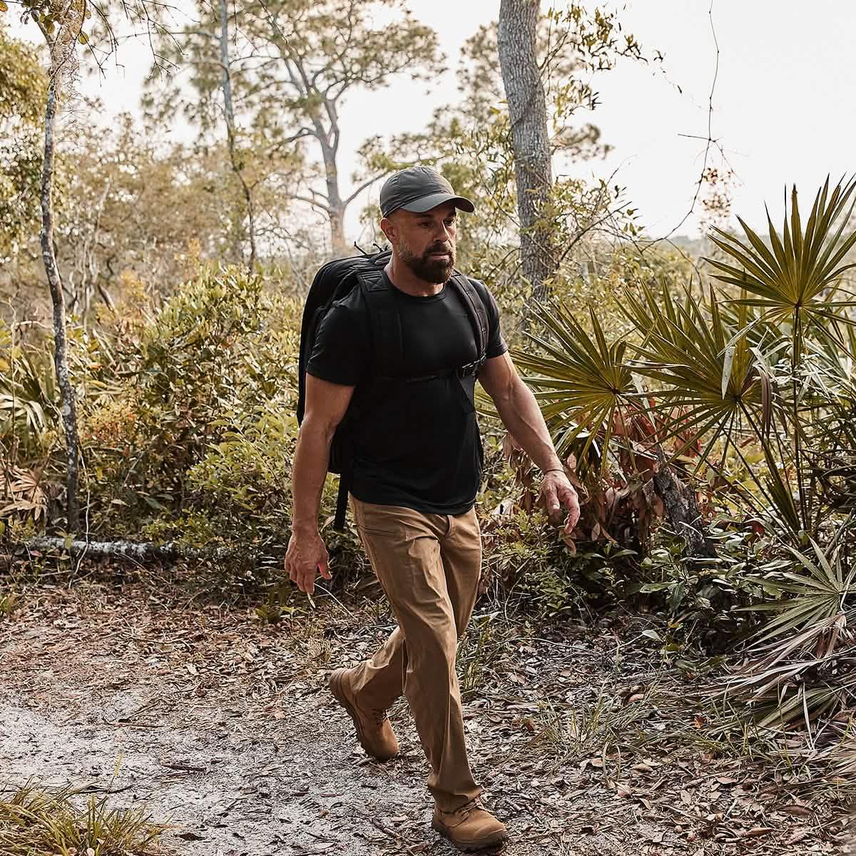 Man rucking with GORUCK backpack and cap on a rugged forest trail outdoors